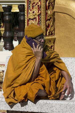 A Thai monk using a cellphone at Doi Suthep Buddhist Temple near Chiang Mai in northern Thailand のeditorial素材