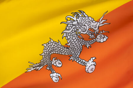 The national flag of The Kingdom of Bhutan - The flag is based upon the tradition of the Drukpa Lineage of Tibetan Buddhism and features Druk, the Thunder Dragon of Bhutanese mythology  の写真素材