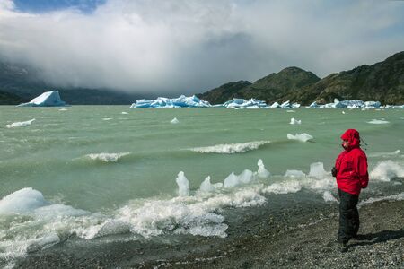Tourist looking at icebergs from the Grey Glacier in Grey Lake in the Southern Patagonian Ice Field in Torres del Paine National Park in southern Chile.のeditorial素材