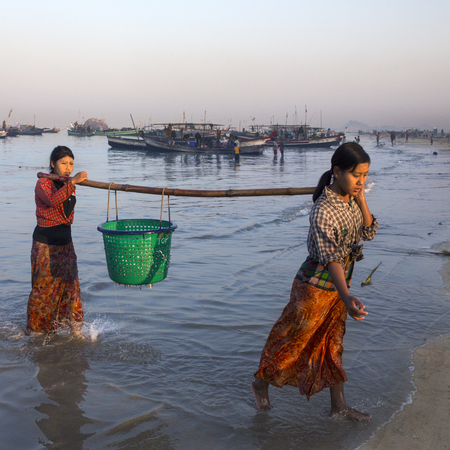 Burmese woman bringing the nights catch ashore at dawn, near the fishing village on Ngapali Beach in Myanmar (Burma).のeditorial素材