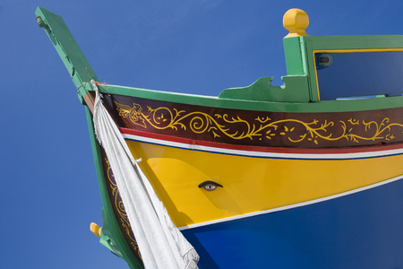 Traditional Luzzu fishing boat in Valletta harbour in Malta. A luzzu is a traditional fishing boat from the Maltese islands. They are usually painted in bright colours, and the bow has a pair of eyes - the Eye of Osiris. Luzzus have existed since ancient の写真素材