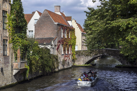 Tourist boat on the canals of the Begijnhof area of the city of Bruges in Belgium.のeditorial素材