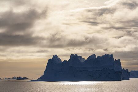 Massive iceberg floating in Scoresbysund in eastern Greenland in the late afternoon sunlight.の写真素材