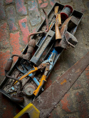 Old tools on the floor a shed with muck and cobwebs.