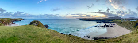 Panoramic view of the rocky coastline and sandy beach at Sangobeg Sands in the dawn sunlight.  Sutherland on the north coast of Scotlandの写真素材