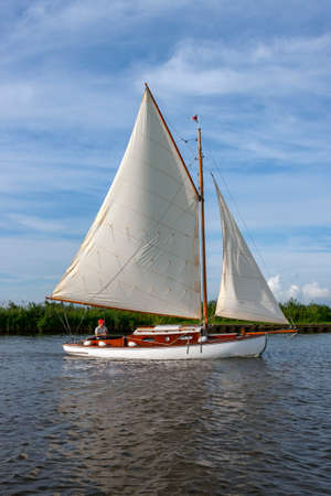 Yacht sailing on the Norfolk Broads, United Kingdom - a network of shallow freshwater lakes,...