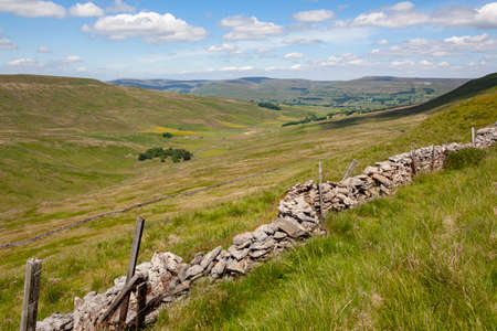 Traditional dry-stone walls and barns in the farmland of the Yorkshire Dales in northeast England.