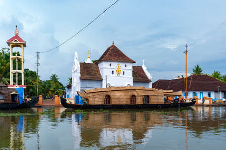 Tourist rice barge (houseboat) moored near a Christian Church on the inland waterways of the Kerala Backwaters, near Kochi in southern India.のeditorial素材