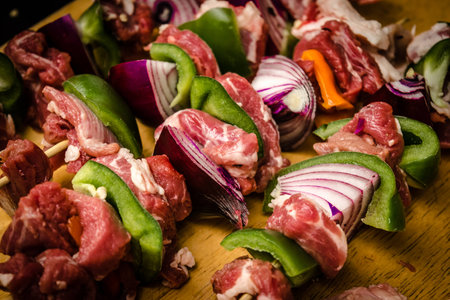 Uncooked beef and pork skewers with green, orange pepper and onionsの写真素材
