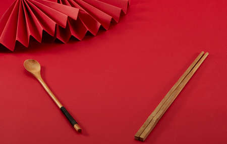 Red folding fans, wooden spoon and chopsticks on red backgroundの写真素材