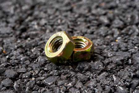 Close-up of two screw nuts on asphalt