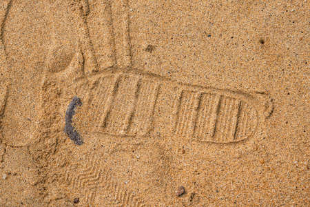 Close-up of shoe print stepped on by slippers on beach by the sea