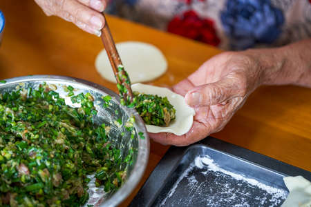An old man in a Chinese family makes dumplings by handの写真素材