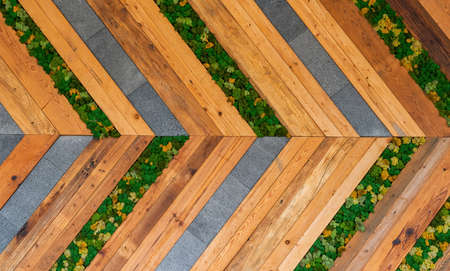 A right arrow wall made up of wooden and stone strips and plantsの写真素材