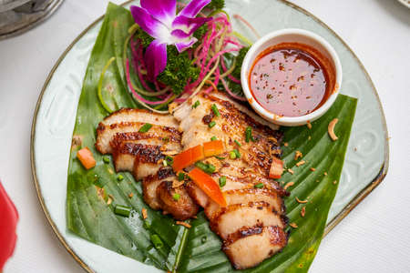 A plate of crispy and delicious roasted pork neck with Thai chutney
