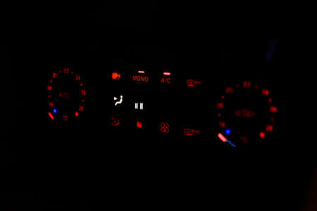 Close-up of the lights of the air conditioning control panel of a car at night