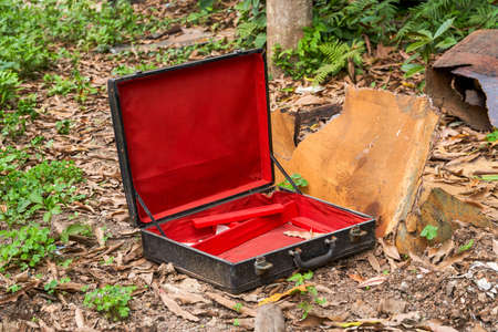 An abandoned red and black empty suitcase in the wild