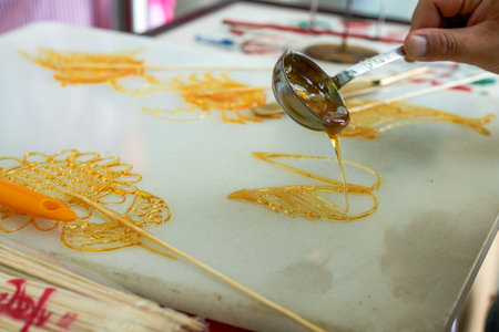 A craftsman is making traditional Chinese snacks, painting sugar paintings