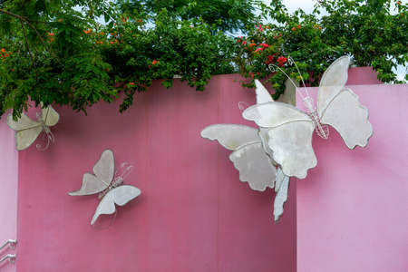 Fabric winged butterfly statue on pink wall outdoorsの写真素材