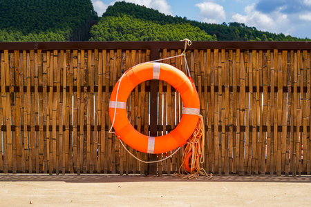 Close-up of orange lifebuoy on shore of lake in park outdoorsの写真素材