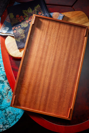 Empty wooden serving plate set against southeast asian tropical tablecloth and decorative boardの写真素材
