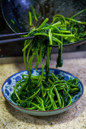 A chef is serving a plate of fried sweet potato leaves