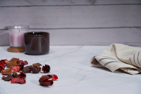 Cozy home scented candle and dried flower petals napkin backgroundの写真素材