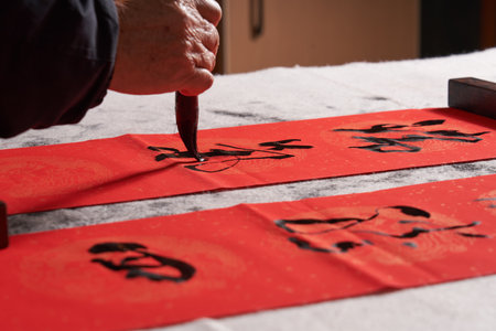 An old calligrapher writes couplets during the Chinese Year of the Dragon. Translation: The auspicious energy brings auspiciousness and the wealth is abundant.の写真素材
