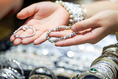 Close-up of female hands holding silver bracelets in a shopの写真素材