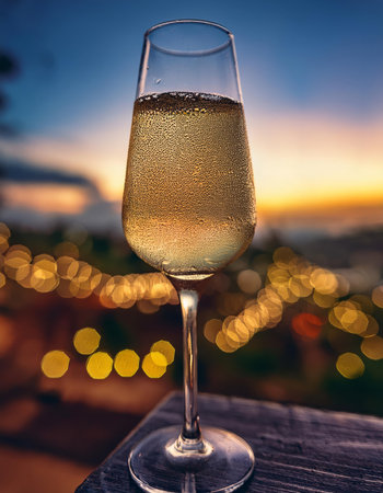 Glass of champagne on the terrace of a restaurant with view on the city at sunsetの素材