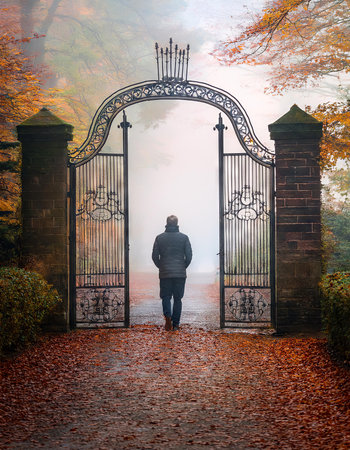 A man walking through a gate on a foggy autumn day.の素材