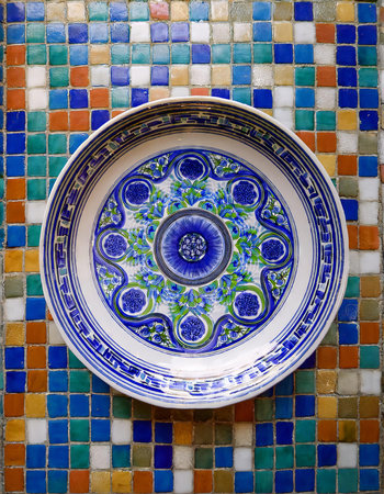 Blue and white porcelain plate on a colorful mosaic background.の素材