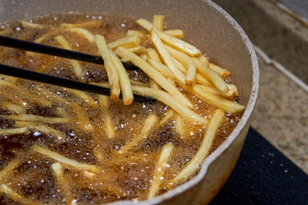 A chef frying French fries in the kitchen