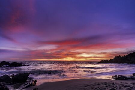 Colorful sunset at Moss Cove in Laguna Beach, Southern California. A slight long exposure to show the ocean retreating back from the beach and out to sea.の写真素材