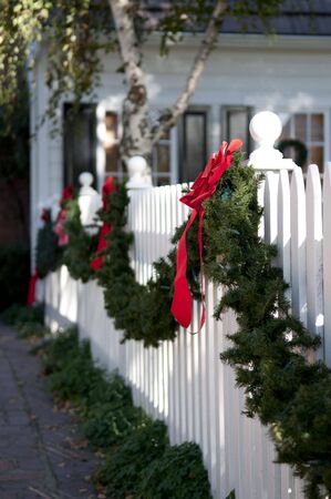 garland with red bows hanging on white picket fenceの写真素材