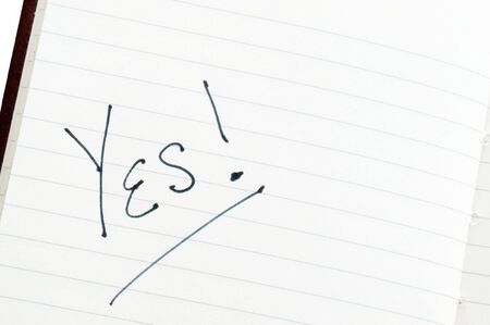 Word "yes" written in black ink on lined paperの写真素材