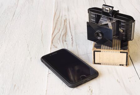 Antique film camera and smartphone illustrating changes in technology, new and old, shot against...