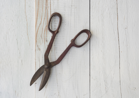 pair of antique, rusted vintage tin snip tool against weathered white painted wood background