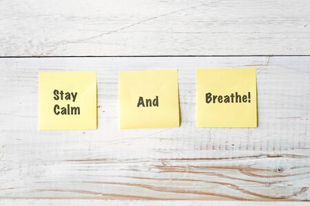 three yellow notes with message Stay Calm and Breathe! against weathered white wood background
