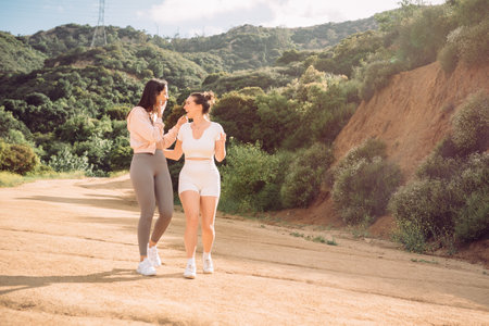 Two women in workout clothing taking a hike and sharing some gossip