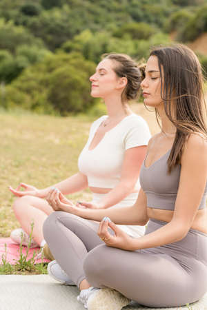 Two attractive, fit young women meditating outside in natureの写真素材
