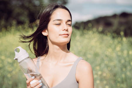 Young woman with dark hair enjoying sunshine with eyes closedの写真素材