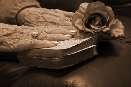 Senior's hands resting on a very old bibleの写真素材