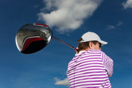 A golfer swinging a large driver (focus on golf club)の写真素材