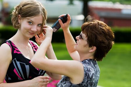 A mother fixes her daughters hair before a dateの写真素材