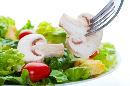 healthy salad appetizer with a raw mushroom on a forkの写真素材