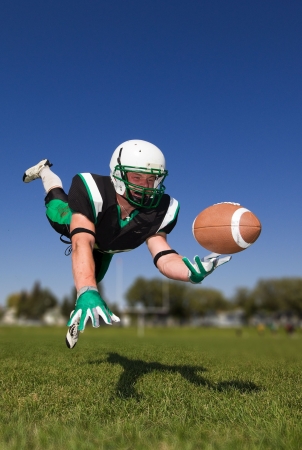 American football player diving and catching the ballの写真素材