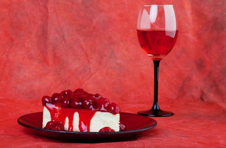 cherry cheesecake served on a candy apple red plate with red wine,on a red background.の写真素材