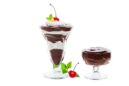 A layered chocolate parfait with a small pudding.Garnished with whipped cream, cherries, and  lemon balm.  の写真素材