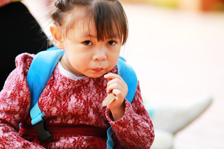 Cute little girl sitting on the floor staring at the cameraの写真素材